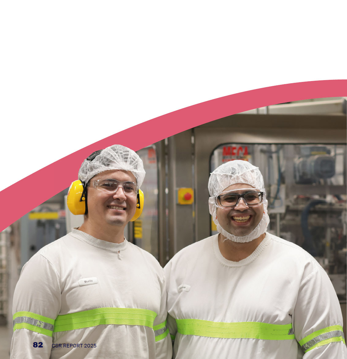 Photo of two employees, in a factory, smiling at the camera